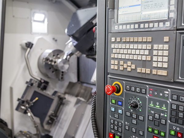 The control panel of a CNC machine with buttons, screens and LEDs