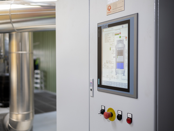 Control panel for hot water boiler with pipe installation in background