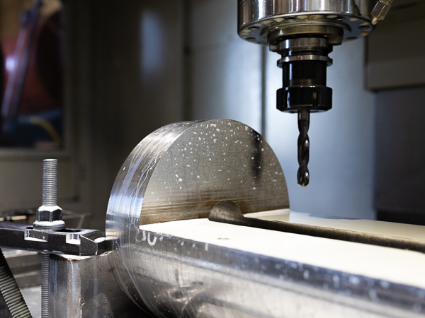 A CNC machine drill making a precise hole in a metal sheet.