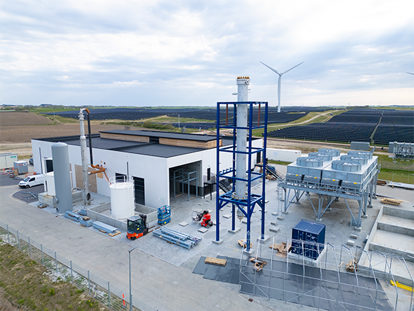 Power-to ammonia plant under construction with wind turbine and solar park in the background