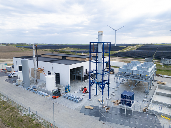 Power to X plant under cunstruction with wind turbines and solar panels in the background