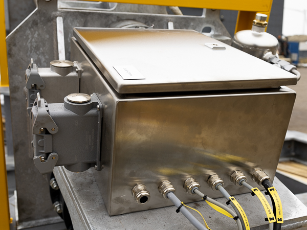 Rustfri kasse med kabelindgange samt stik til strøm monteret på et spil