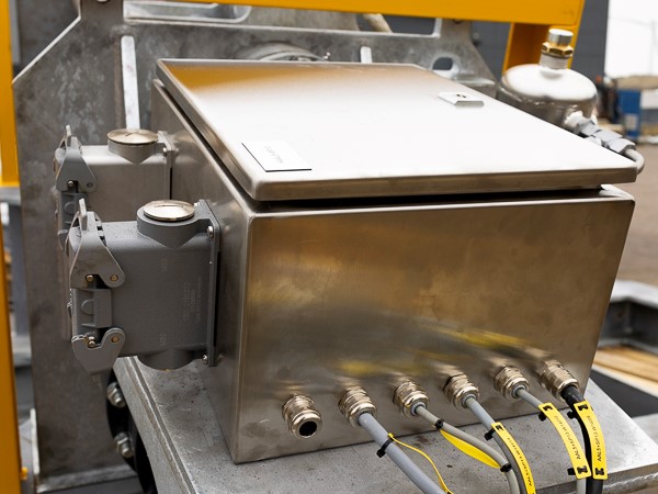 Rustfri kasse med kabelindgange samt stik til strøm monteret på et spil