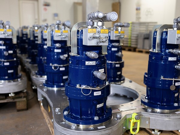 Assembly of hydraulic Turner Gear units with blue cabinets and connection pipes on a production line.