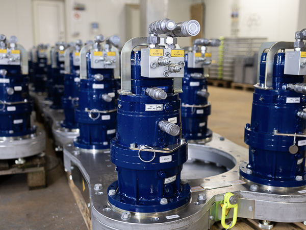 Samling af hydrauliske Turner Gear enheder med blå kabinetter og tilslutningsrør på en produktionslinje.