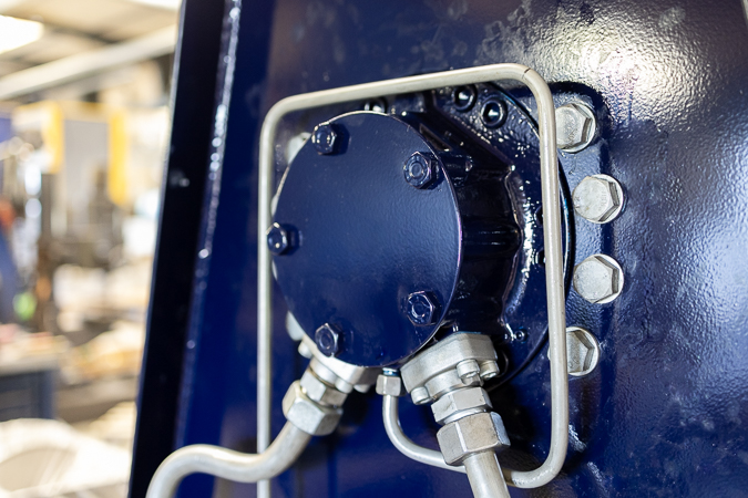 Detailed view of the hydraulic system of the custom-made net drum, focusing on the piping and connection components in a well-lit workshop.