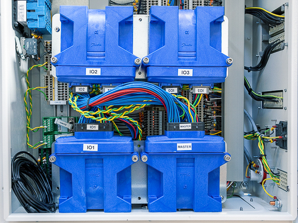 A close-up view of a control panel with a digital screen, surrounded by metal casing and protective handles, used for monitoring or operating industrial equipment.