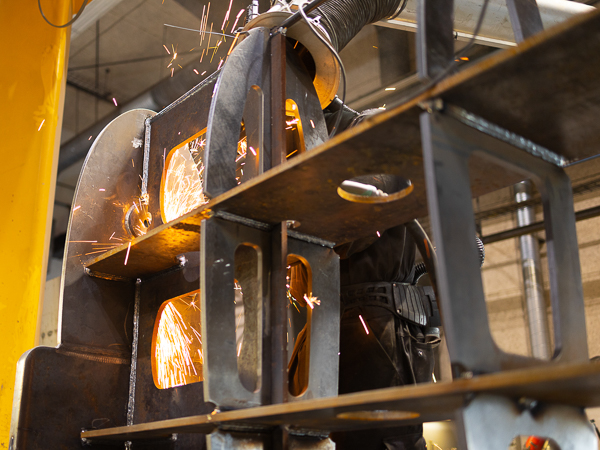 A welder works with flying sparks while welding the steel construction.