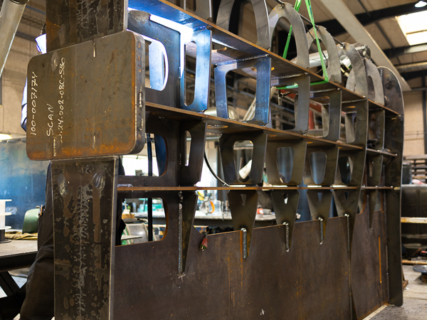 Steel structure for a large rudder under construction in a production hall.