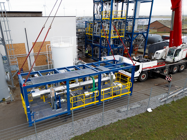 Crane lifts module over the safety fence and into the construction site.