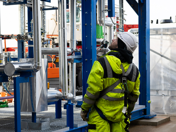 Workers in fluorescent safety clothing closely inspect the installation.