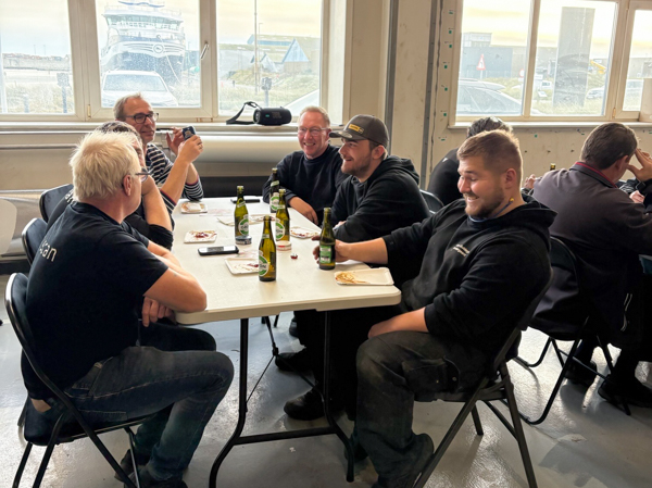 Group of employees sitting around a table with food and drinks, enjoying the informal Friday gathering.