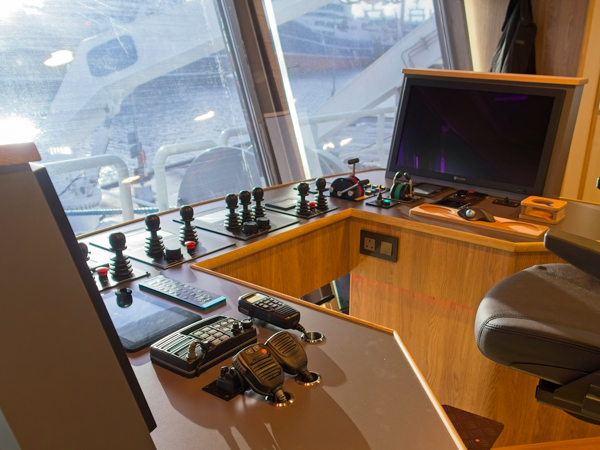 Den moderne bro på Vigilant set fra skipperens stol. En ergonomisk U-formet pult rummer AS-SCANs kontrolsystemer og adskillige joysticks til manøvrering. Gennem vinduerne er der direkte udsyn til dækket og de tekniske anlæg agterud.