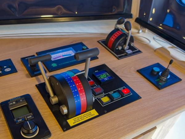 Detaljebillede af operatørpladsen på broen, hvor rækker af joysticks giver præcis kontrol over fartøjets styremaskine og hjælpesystemer. Pladsen er udstyret med AS SCAN joystick og rorindikator.