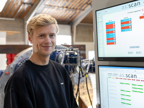 Wind turbine technician standing next to diagnostic screens displaying system data during Turner Gear training and troubleshooting session at AS SCAN.