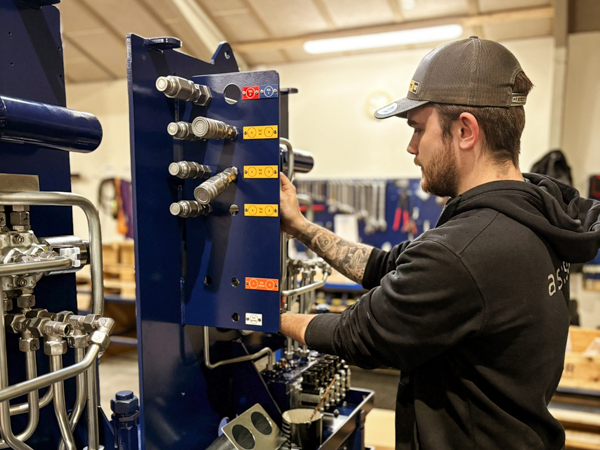 AS SCAN technician connecting hydraulic components on a Turner Gear control station during assembly at the workshop.