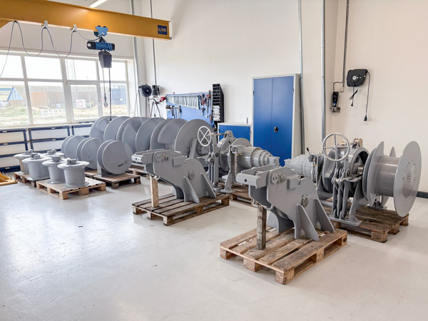 New assembly facility with staged anchor winches and deck equipment on pallets, prepared for marine installations