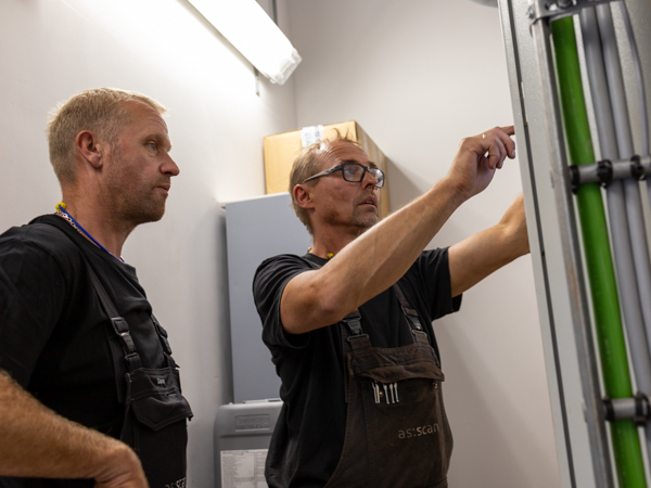 Two AS SCAN technicians inspecting components in an industrial installation.